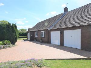 uma casa de tijolos com duas portas de garagem brancas em 3 Bed in Fakenham 56661 em Whissonsett