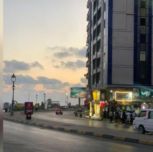 een straat met een gebouw en een straat met auto's bij Lovely apartment with side sea view located in the heart of the Alexandria in Alexandrië