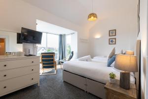 a bedroom with a bed and a dresser with a television at Y Glan Neigr in Rhosneigr
