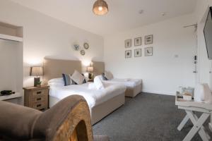 a bedroom with two beds and a desk with a chair at Y Glan Neigr in Rhosneigr