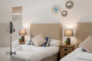two beds in a bedroom with clocks on the wall at Y Glan Neigr in Rhosneigr