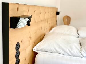 a bed with a wooden headboard with white pillows at Hotel Central La Fainera Superior in Valchava