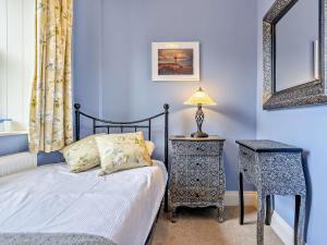 a blue bedroom with a bed and a table and a mirror at 3 Bed in Bamburgh CN022 in Smeafield