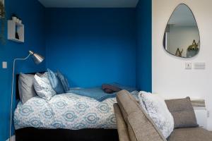 a blue bedroom with a bed and a mirror at Brand New Studio Apartment in Sheffield in Sheffield
