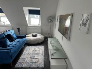 Dartford Town 3 Bed by Harlington في Kent: غرفة معيشة مع أريكة زرقاء وطاولة