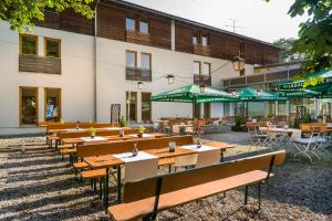 ein Restaurant mit Holztischen und -stühlen vor einem Gebäude in der Unterkunft Hotel Seidlhof in Haar