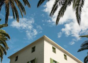 un edificio blanco con palmeras en el primer plano en Demeure Castel Brando Hôtel & Spa en Erbalunga