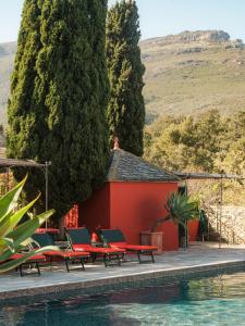 een resort met een zwembad met stoelen en een gebouw bij Demeure Castel Brando Hôtel & Spa in Erbalunga