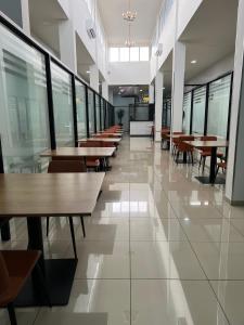 eine leere Cafeteria mit Tischen, Stühlen und Fenstern in der Unterkunft Ixoras Hotel Victoire in Kinshasa