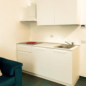 una cocina con armarios blancos y fregadero en Hotel Vienna, en Pesaro