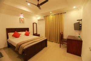 a bedroom with a bed with red pillows and a television at Diamond Residency in Alleppey