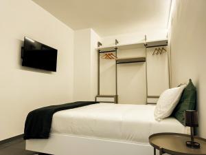 Hotel Vienna في بيزارو: غرفة نوم بيضاء مع سرير وتلفزيون