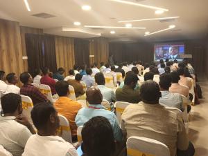 eine Gruppe von Menschen sitzt in einem Raum und sieht sich eine Präsentation an in der Unterkunft SAS SQUARE in Tiruchchirāppalli