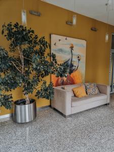 un sofá y un árbol en una habitación con una pintura en Hotel Azyl, en Kąty Wrocławskie