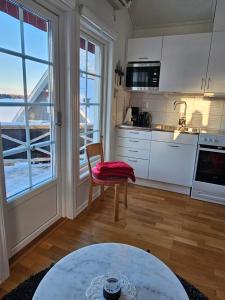 cocina con armarios blancos, mesa y ventana en Toppstugan, en Åkerö