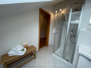 a bathroom with a shower and a bench with towels at Ferienwohnung Huimelig im Allgäu in Röthenbach