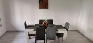 une table à manger avec des chaises noires et un vase de fleurs dans l'établissement Perpignan Parc des sports-15min de la mer, à Perpignan