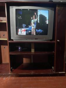 un televisor en un soporte de madera con una persona en él en Casa para temporada em um paraíso tropical en Cananéia