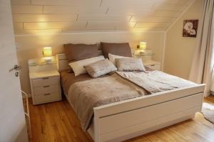 a bedroom with a large white bed with two lamps at Ferienhaus Eifelwind Kamberg in Hellenthal