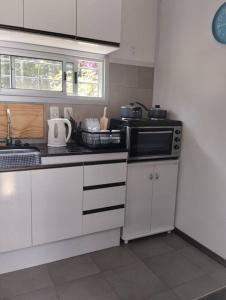 een keuken met witte kasten en een magnetron bij Casa contenedor super cómoda in La Floresta