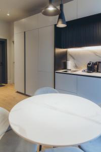 uma cozinha branca com uma mesa e cadeiras brancas em Apartments Vitenberg em Cēsis