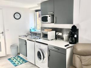 a kitchen with a washing machine and a microwave at Studio indépendant confortable in Bourbon-lʼArchambault