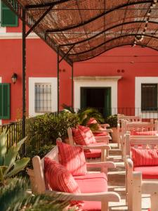 une rangée de chaises longues devant un bâtiment rouge dans l'établissement Demeure Castel Brando Hôtel & Spa, à Erbalunga