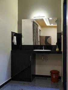 La salle de bains est pourvue d'un lavabo noir et d'un miroir. dans l'établissement Coconut Homestay Hampi, à Hampi