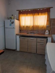 a small kitchen with a sink and a refrigerator at Casa V.Giardino pileta y cochera in Villa Giardino