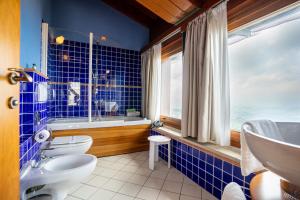 Baño de azulejos azules con 2 aseos y lavamanos en Hotel Cesare en San Marino