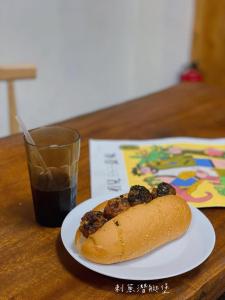 einen Hot Dog auf einem Teller neben einem Glas Soda in der Unterkunft Vuluq in Shoufeng