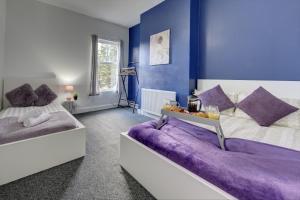 Cosy 3BR Gem, Sleeps 6, Near Town Centre في كوفينتري: سريرين في غرفة بجدران زرقاء
