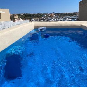 a blue swimming pool with a white chair in it at Hotel Medusa in Lampedusa