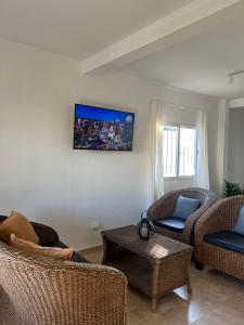 a living room with two chairs and a tv on the wall at Duplex del Río in Concordia