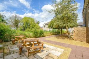 a patio with two benches and a table at Two Bedroom Duplex Apartment The Priory in St Ives