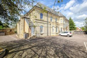 un viejo edificio con un coche aparcado en un estacionamiento en Two Bedroom Duplex Apartment The Priory, en St Ives