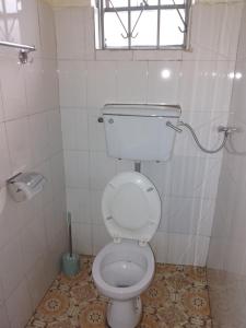 - białą toaletę w łazience z oknem w obiekcie SAWA SAWA GUEST HOUSE w mieście Kisoro
