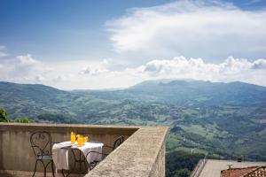 a table and chairs on a balcony with a view of mountains at Hotel Cesare in San Marino