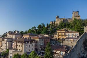 un groupe de bâtiments sur une colline avec un château dans l'établissement Hotel Cesare, à Saint-Marin