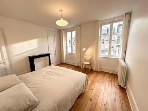 a white bedroom with a bed and two windows at Villa Jean- plein centre Etretat in Étretat