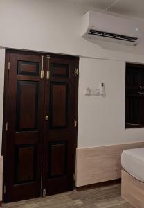1 dormitorio con puertas de madera, 1 cama y ventana en The Branch B&B, en Negombo