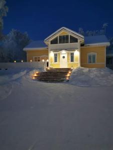 a house with lights in the snow at night at Arctic Lakeside Home in Kemijärvi