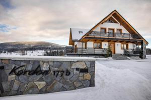 ein Haus im Schnee mit einer Steinmauer in der Unterkunft Domek Kordoń SPA Jacuzzi & Sauna in Zubrzyca Górna