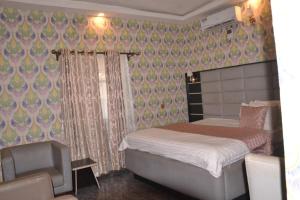 niewielka sypialnia z łóżkiem i krzesłem w obiekcie Rizz Park Hotel & Event Center w mieście Nnewi