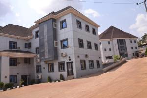 a large white building on a dirt road at Rizz Park Hotel & Event Center in Nnewi