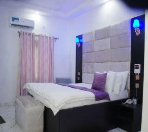 1 dormitorio con 1 cama grande con almohadas moradas en Rizz Park Hotel & Event Center, en Nnewi