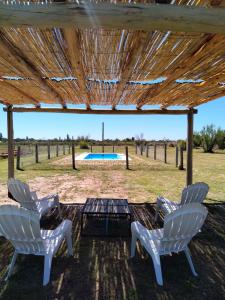 un gruppo di sedie e un tavolo con piscina di Entre fincas alojamiento rural a San Rafael