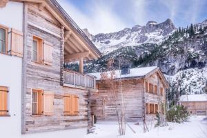 a log cabin in the snow with mountains in the background at Circle Chalets Arlberg in Zug