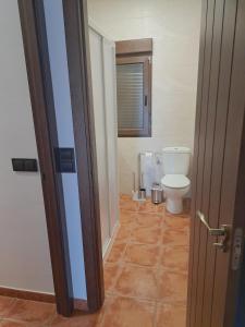 a bathroom with a toilet and a door open at Casa Rural La Veguilla in Argés