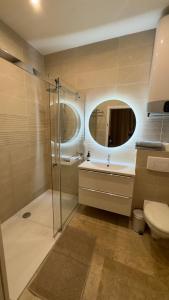 een badkamer met een douche, een wastafel en een spiegel bij By Nuit-Parisienne : city-view in Villemomble